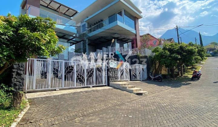 Translation: For Sale Well-Maintained 2-Story Villa Fully Furnished with Investment Potential or Passive Income Move-In Ready Peaceful and Greenery-Filled Environment with City Light and Mountain Views Near Tourist Area Jatim Park 2 and BNS at Villa Panderman Hill Batu I036